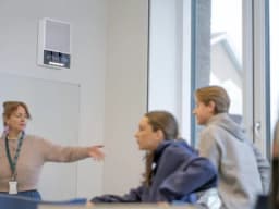 AXIS C1710 from AXIS COMMUNICATIONS - installed in a classroom. The display text is Attention and the teacher and studnets are prepring to leave the classroom